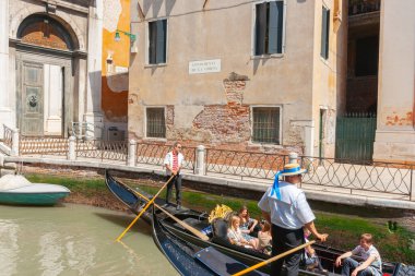 Venice Italy - May 10 2011; Gondola packed with tourists on narrow canals and passing under bridges.