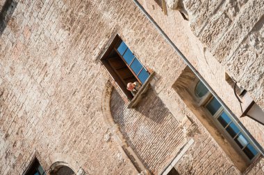 Gubbio İtalya - 13 Mayıs 2011; Avrupa 'daki tipik bir binanın penceresinden bakan adam açısal perspektifte.