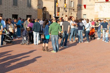 Gubbio Umbria, İtalya-15 Mayıs 2011; Avrupa şehir meydanında güneş batarken ve gölgeler öğleden sonra uzarken insanlar toplanıyor.