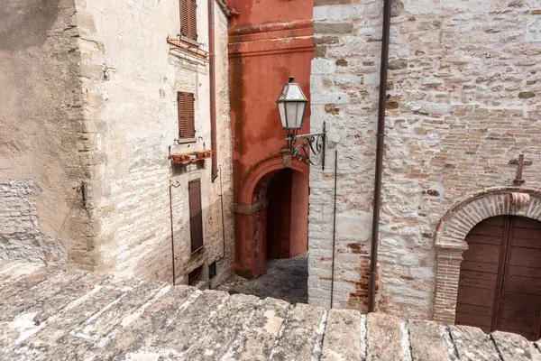 Narrow street or alleyway between ancient European buildings in village of frontone Italy.