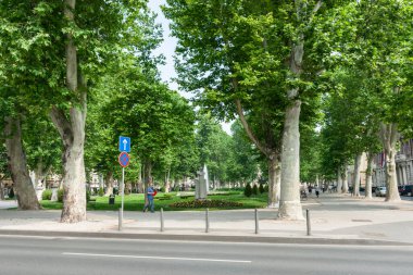 Zargreb Hırvatistan - 23 Mayıs 2011; Lüks şehir parkı ve caddenin karşısında uzun ağaçlar ve yanından geçen bir adam.