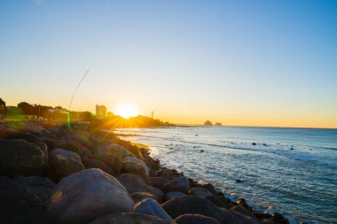 Yeni Plymouth Yeni Zelanda - 28 Şubat 2024; Güneş ve Yeni Plymouth elektrik santrali bacası kıyı şeridi manzarası.