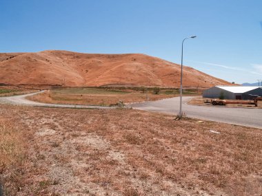 Yazın yeni bir yol olan yeni sanayi arazisi. Renkler bölünmüş ve yol boyunca mavi gökyüzü altında yeni binaların gelişmesini bekliyor..