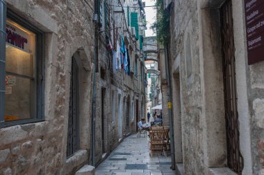 Split Hırvatistan - 26 Mayıs 2011: Çamaşır asma ve tarihi Avrupa kentindeki kafe masalarında insanların bulunduğu eski kentin dar şeridi