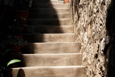 Hırvatistan 'ın Zadar kentinde inşa duvarına karşı koyu gölgeli ve yeşil yapraklı adımlar yukarı doğru ilerliyor.