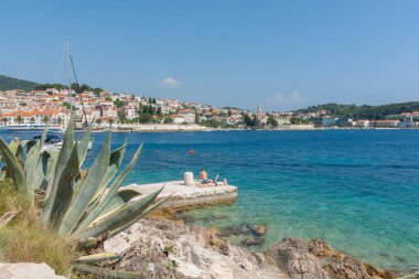 Hvar Hırvatistan 27 Mayıs 2011; Hvar limanının kenarında güneşlenen iki adam ve arka planda kent manzarası.