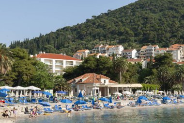 Dubrovnik Hırvatistan - 29 Mayıs 2011; İnsanlar ve mavi şemsiyeli Uvala Lapad plajı.