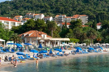 Dubrovnik Hırvatistan - 29 Mayıs 2011; İnsanlar ve mavi şemsiyeli Uvala Lapad plajı.