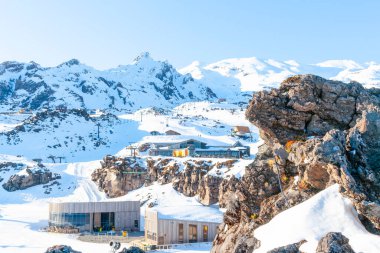 Whakapa kayak pisti yamaçları ve tesisleri Yeni Zelanda 'da güneş doğarken dağın gölgeli tarafındaki binalar