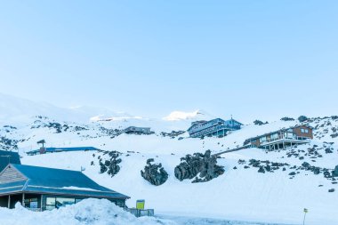 Whakapa kayak sahası. Yeni Zelanda 'da güneşin doğuşu gibi dağın gölgeli tarafında pansiyon binaları var.