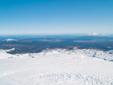 Yukarı Ruapehu Dağı 'nın karlı önplanıyla Kuzey Adası boyunca geniş bir manzara var..