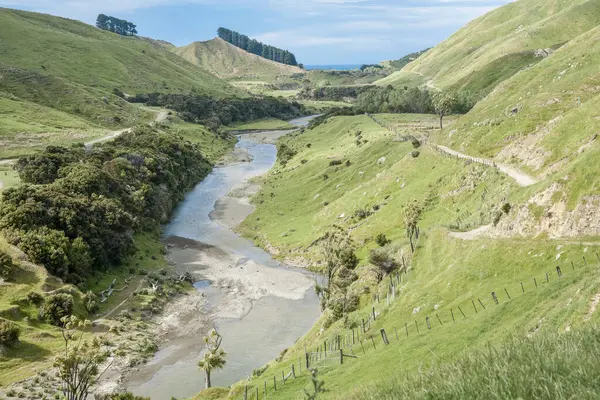 stock image Dirt track and fence-line along hillside following river below in valley of New Zealand farm.