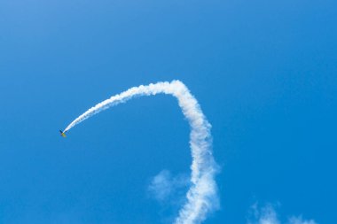 Küçük klasik uçak 2012 Airshow sırasında Maunganu Dağı 'nda mavi gökyüzünde buhar izi bırakır.
