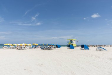 Miami Florida Amerika - 28 Haziran 2012; Sahilde yaz günü sarı ve mavi şemsiyeli insanlar.