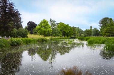 Woodstock United Kingdom - July 25 2024; people in distance walking around lake in expansive garden. clipart