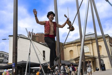 Oxford Birleşik Krallık - 25 Temmuz 2024; keman çalarken gevşek çizgi üzerinde dengede duran sokak göstericisi.