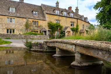 Cotswold 'daki küçük İngiliz köyü Lower Slaughter' da akarsu üzerindeki alçak taş köprü..