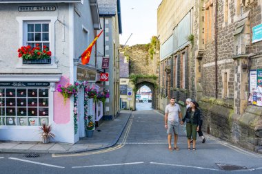 Conwy Wales - 30 Temmuz 2024; Şehrin ana caddesi eski şehir duvarından limana ve yürüyen turistlere kadar manzaralı .