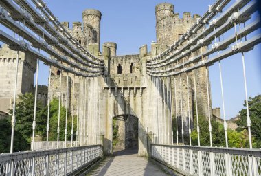 Suspension cables of bridge and path provide leading lines of bridge to Conwy Castle entry in portrait aspect ratio. clipart