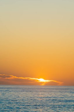 Sahilde altın gün doğumu denizin üzerinde ve uzak ufukta
