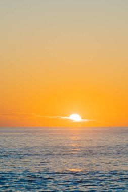 Sahilde altın gün doğumu denizin üzerinde ve uzak ufukta