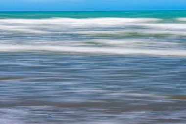 Horizontal white waves along beach blurred using intentional camera movement at Waimarama in Hawkes Bay. clipart