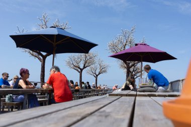 Aberystwyth Birleşik Krallık - 2 Ağustos 2024; Royal Pier Arcade rıhtımındaki açık hava yemek masaları gündelik ortamında güneş ve yiyecek ve içeceğin keyfini çıkarıyor.