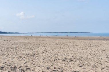 Harlech Wales - August 1 2024; Expansive view of scenic Harlech Beach with insignificant people enjoying outdoors and sand to waters edge and horizon in North Wales. clipart