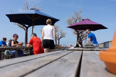 Aberystwyth Birleşik Krallık - 2 Ağustos 2024; Royal Pier Arcade rıhtımındaki açık hava yemek masaları gündelik ortamında güneş ve yiyecek ve içeceğin keyfini çıkarıyor.