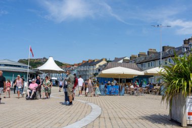 Aberystwyth Birleşik Krallık - 2 Ağustos 2024; İnsanlar Galler tatil beldesi MArine Terasında güneşli bir günün tadını çıkarıyorlar.