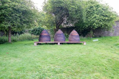 Beehives in old-fashioned stacked circular ring style like skeps grass lawn in United Kingdom. clipart