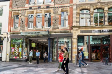 Cardiff Wales - 6 Ağustos 2024: The Hayes 'teki Royal Arcade girişinin önünden geçen iki kadın, kaldırım boyunca yürüyen insanlarla birlikte yürüdü.