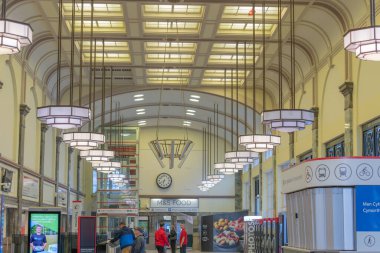 Cardiff Wales - 6 Ağustos 2024; Salon içinde insanlar bekliyor ve kapıda ve kemerli yapının altında ticari tabela.