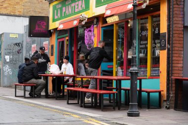 Cardiff Wales - 7 Ağustos 2024 Quay Caddesi 'ndeki renkli taco barın dışında yemek yiyen insanlar.