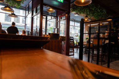 Cardiff Wales - 7 Ağustos 2024; Karanlık kereste ve mobilyalarla loş barın içi gün ışığında pencereden sokağa aydınlatıldı.