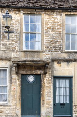 Lacock Birleşik Krallık - 9 Ağustos 2024; Sokak sahnesi ve resim gibi bina yazı tipi cephe yeşil kapı ve saat ile küçük bir İngiliz köyünde dekor film ve drama olarak kullanımıyla ünlüdür.