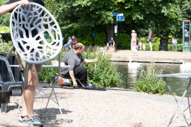 Newbury Birleşik Krallığı - 11 Ağustos 2024; Balıkçı kafeterya müşterisi sandalyesini değiştirirken yakalanan küçük balığı tutuyor.