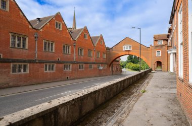 Marlborough United Kingdom- August 11 2024; Marlborough College red brick buildings on both sides of street with enclosed bridge between. clipart