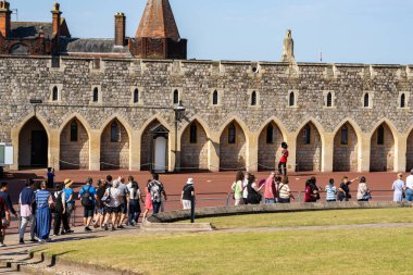 Windsor United Kingdom - August 12 2024; View of lawn and red road with tourists and one Guard marching. clipart