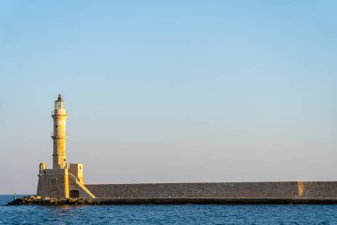 Chania - Girit - 16 Ağustos 2024; Girit 'teki Hanya limanını koruyan uzun dalgakıranın sonunda tarihi Venedik deniz fenerinde önemsiz bir kişi.