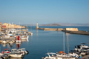 Chania - Girit - 17 Ağustos 2024; Dalgakıran ve deniz feneriyle limandaki tekne ve marina manzarası.