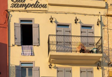 Chania Crete - August 16 2024; Early morning Street view of typical old building with shutters and balcony now used for apartment or hotel in morning light. clipart