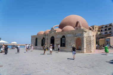 Chania Girit - 15 Ağustos 2024; Turistler Kubbeli tarihi caminin yanındaki güvertede güneşli bir günün tadını çıkarıyorlar.