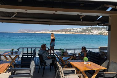 Chania Girit - 15 Ağustos 2024; Restoran müşterileri tentenin altında ve gölgede oturuyorlar..