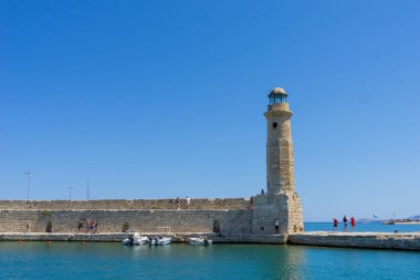 Rethimno Girit - 18 Ağustos 2024; Venedik limanındaki Mısır deniz fenerini keşfeden dalgakıran turistler.