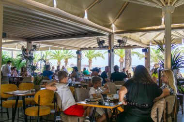 Rethimno Girit - 18 Ağustos 2024; Popüler turizm beldesinde kaldırım boyunca mağazaların restoran masalarına açıldığı kentsel sokak sahneleri.