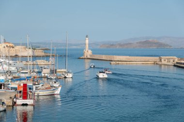 Chania Girit - 18 Ağustos 2024; yat limanında tekneler ve limandan ayrılan deniz feneri