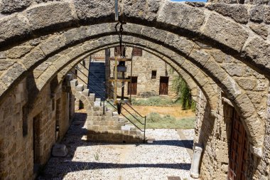 Rodos 'taki Aziz Georges Kilisesi' nin bahçesindeki taş kemerlerle çerçevelenmiş avlu..