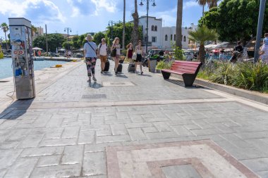 Kos Yunanistan - 21 Ağustos 2024; Rıhtım boyunca yürüyen turistler seyahat çantaları taşıyorlar.