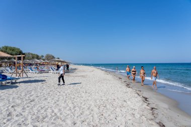 Kos Yunanistan - 25 Ağustos 2024; Sahilde dört yaşlı yetişkin veya güneşli Akdeniz gününde sahil kıyısı boyunca yürüyen yüzme kostümü